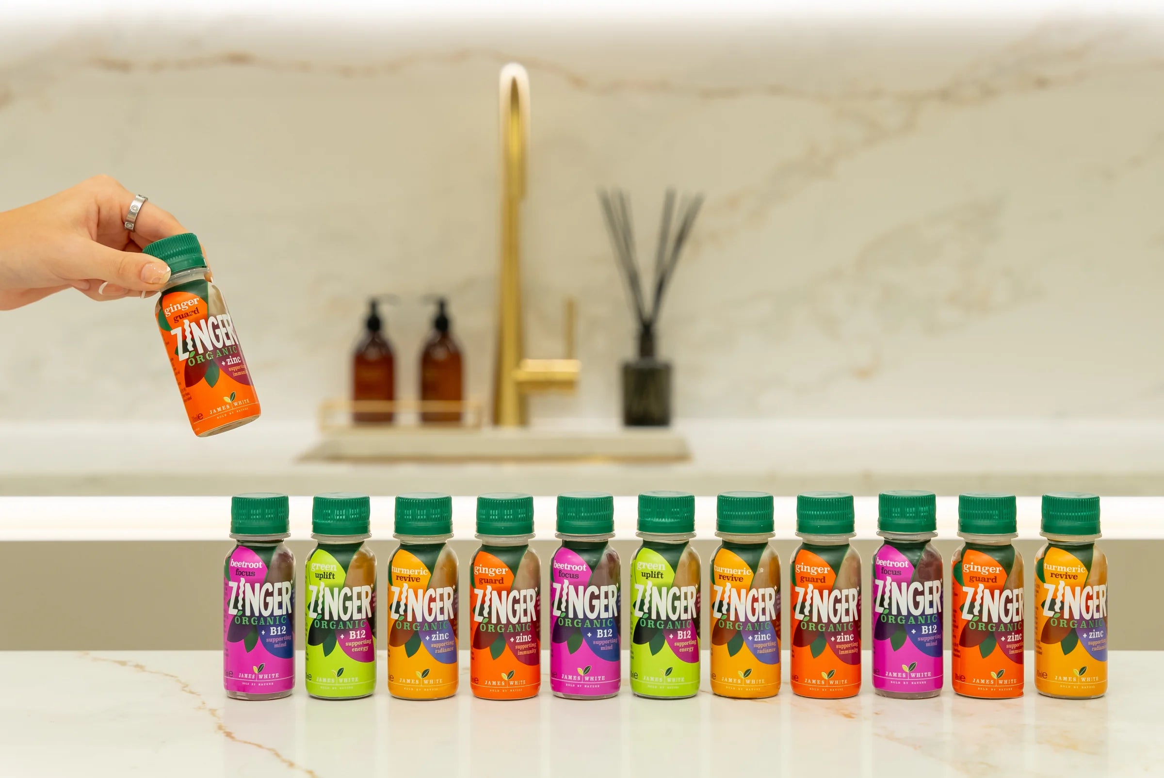 A hand choosing a Ginger Guard shot from the Zinger range on a kitchen counter