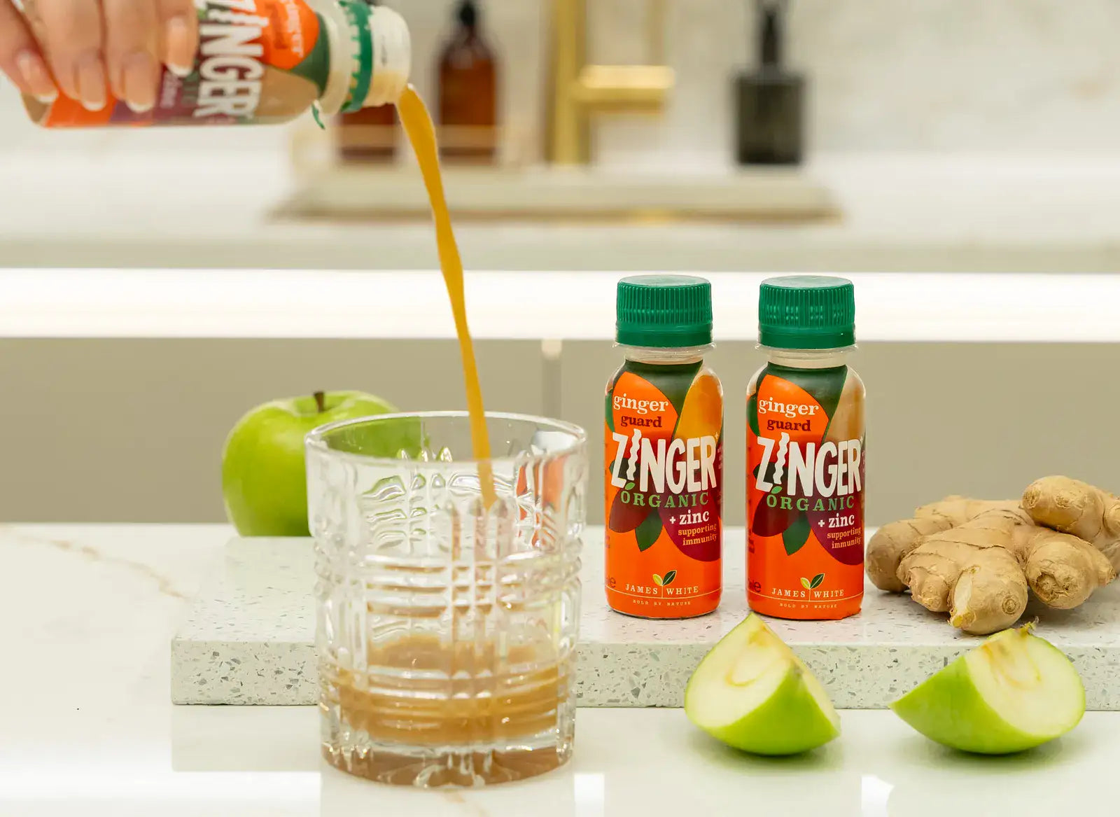 Ginger Guard shots and fresh ginger beside a glass being filled