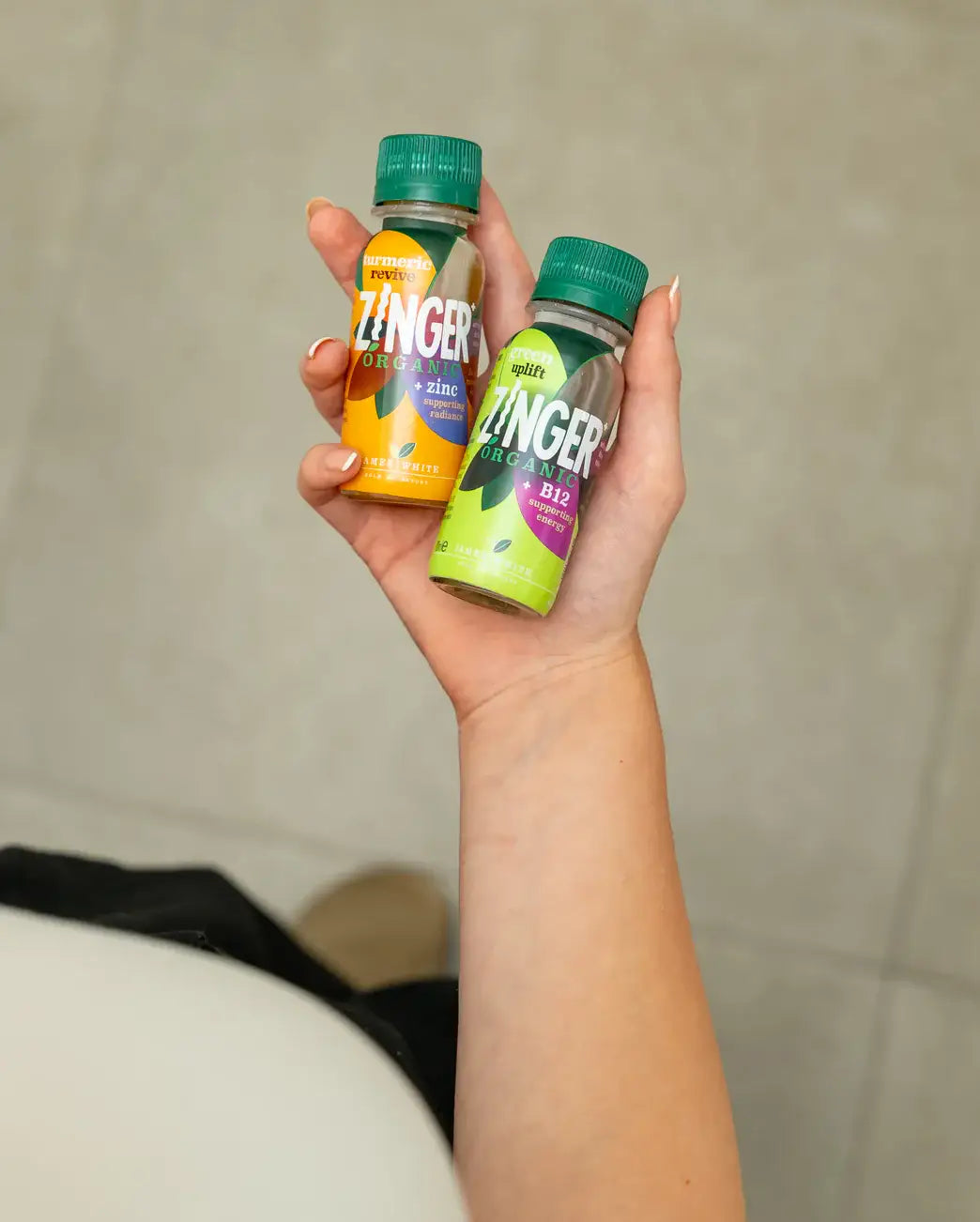 A hand holding Turmeric Revive and Green Uplift shots